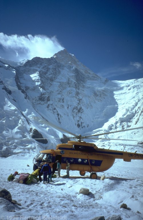 The helicopter is landing on the glacier in front of the camp.