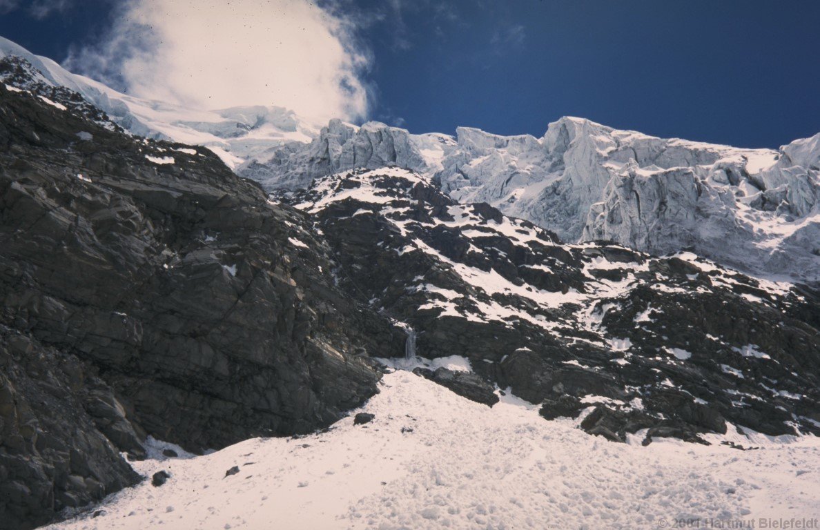 The rock step, in the middle the fixed rope is visible. The ascent route is on the right side of the gully.